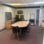 photo of pilots lounge with table and chars. Small desk in background with chalk board on it